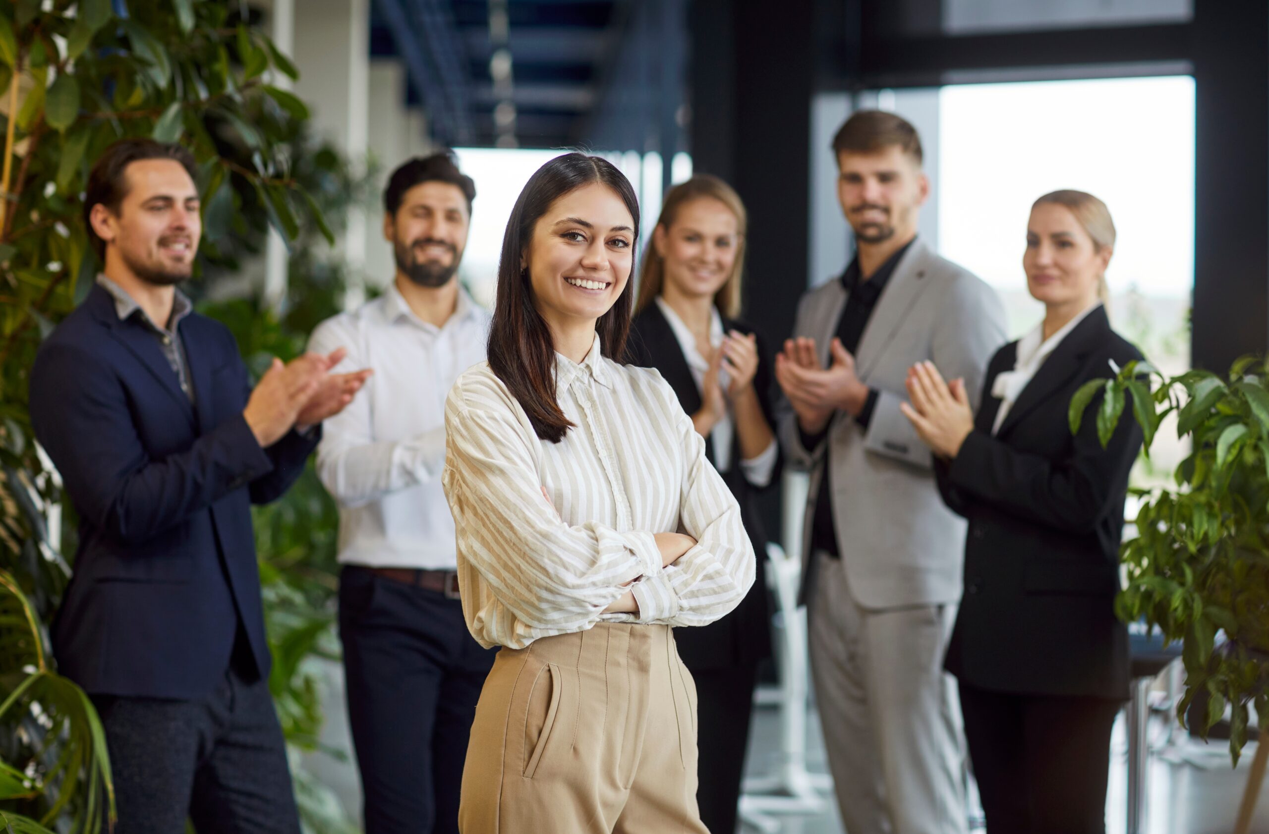 A young business professional being celebrated by her peers in the office.